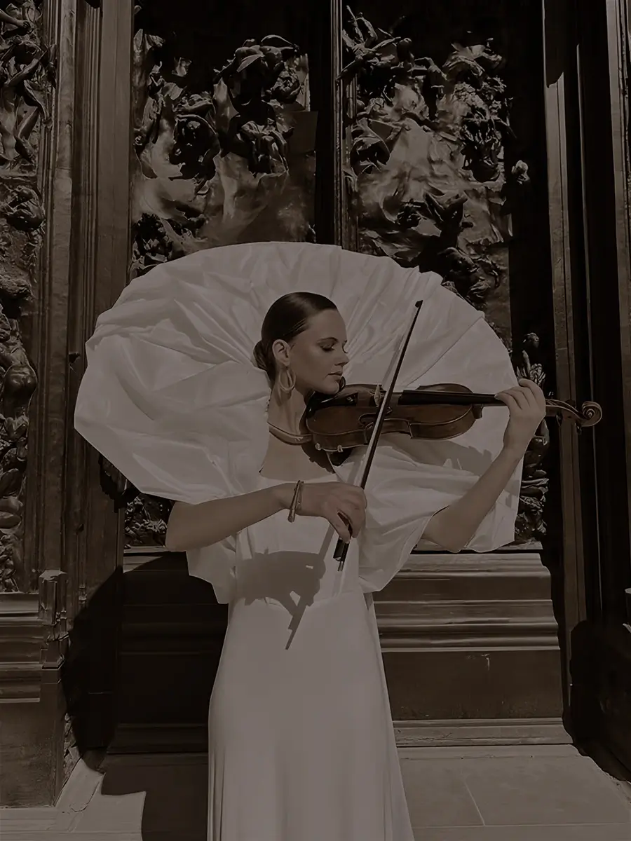 Galina Lanskaia jouant du violon en robe blanche, une ombrelle ouverte derrière elle
